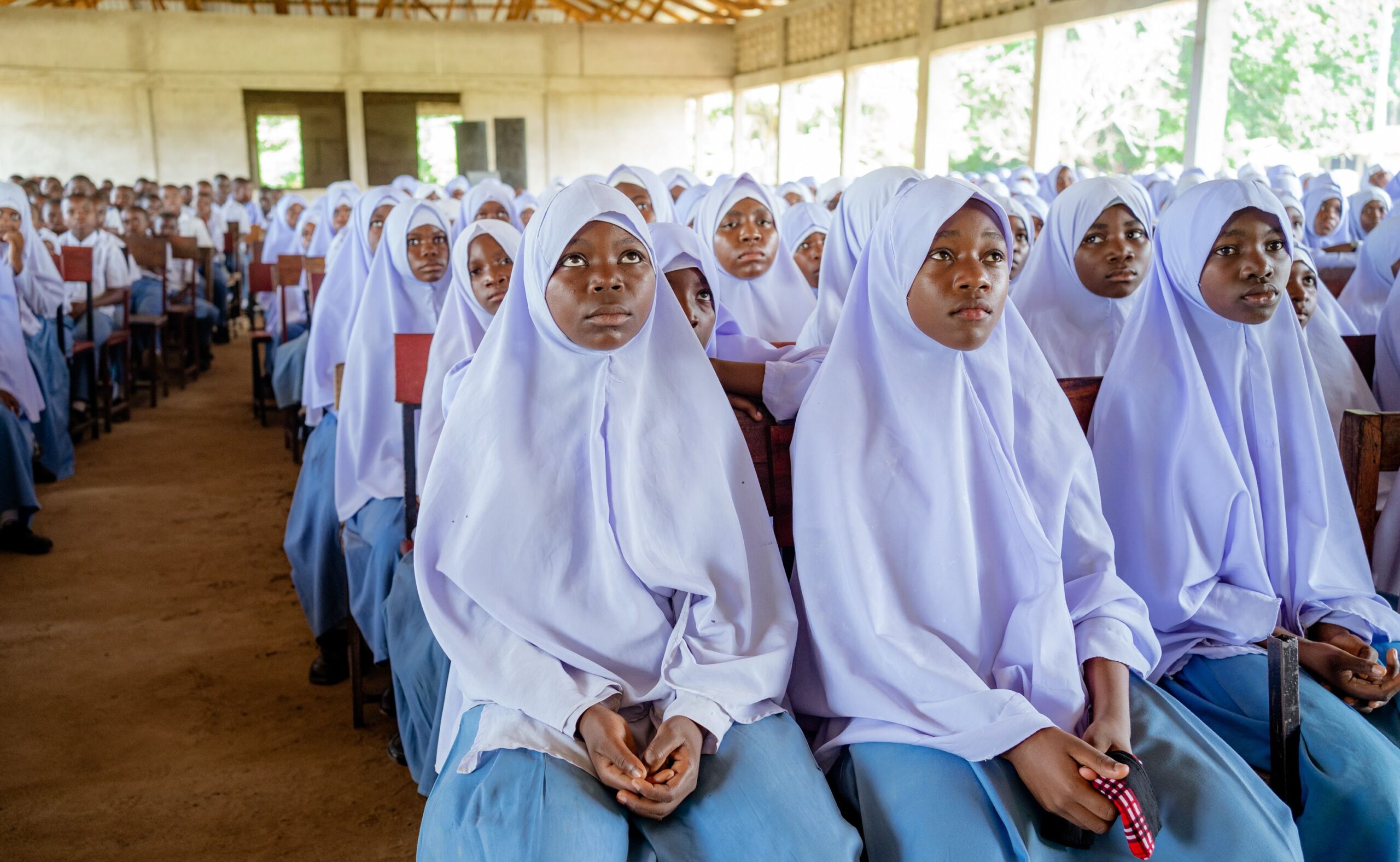 A diverse group of students in uniform attending a school assembly in Africa.